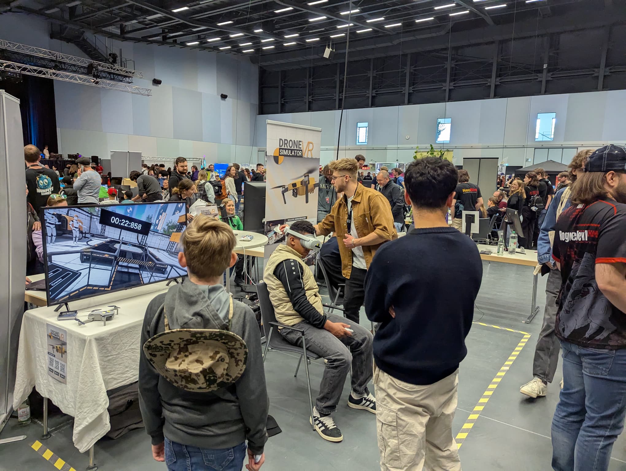 Founder of 0Space demonstrating Drone Simulator VR to new users at a trade fair, with live wireless streaming to an external screen