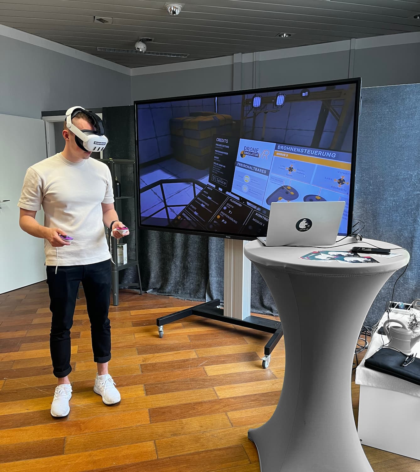User independently adjusts settings and preferred control mode in Drone Simulator VR while using headset and controller in front of a large screen